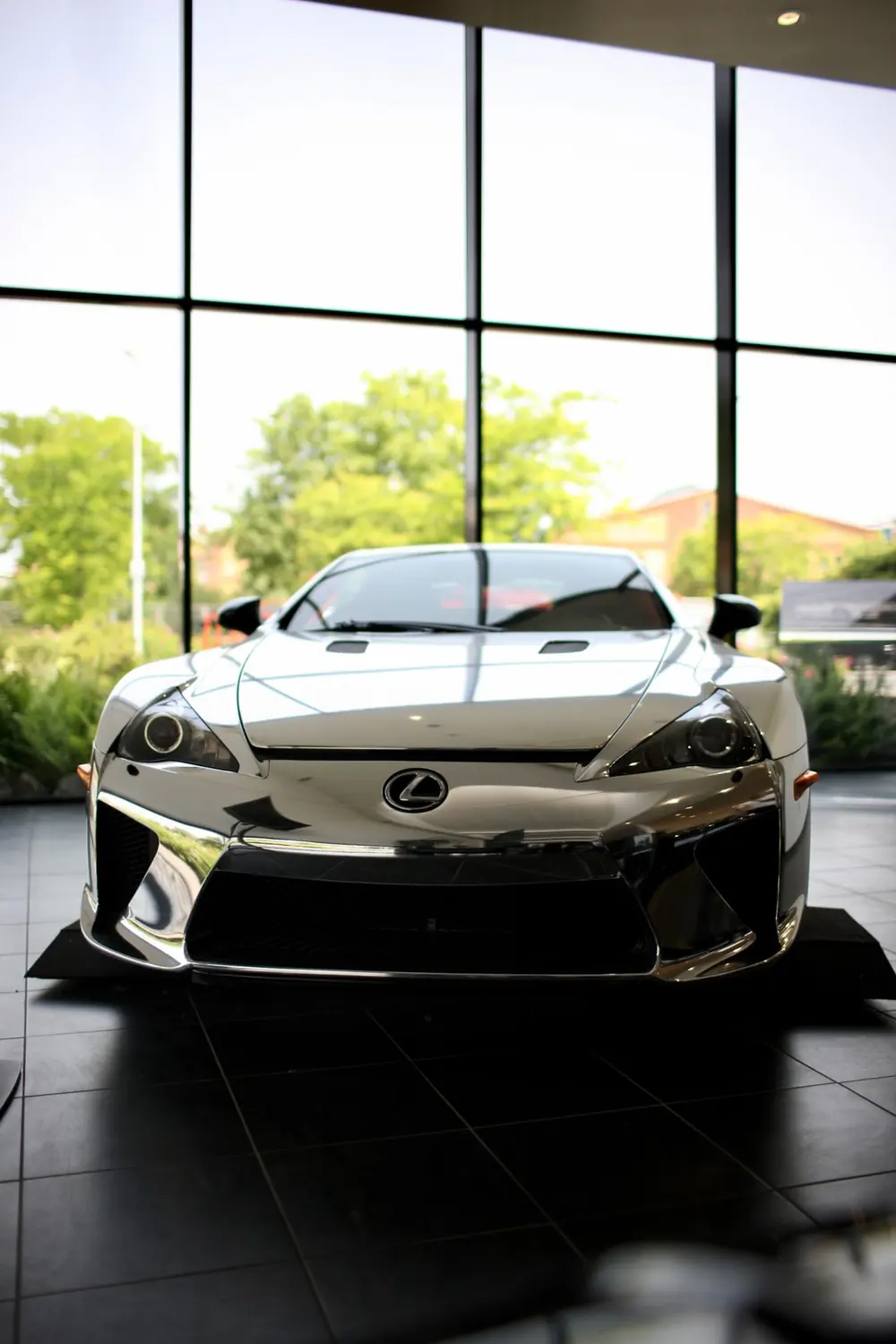 Silver Lexus LFA supercar displayed in a glass-walled dealership showroom