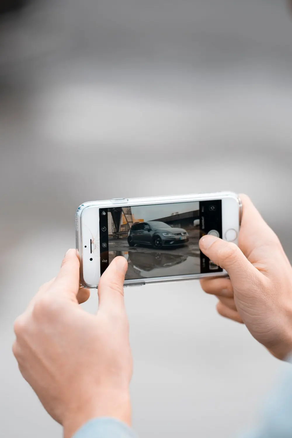Hands framing a listing photo of a car on a smartphone